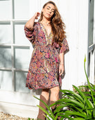Kirra Pink Mini Dress featuring a vibrant paisley print in pink, navy, and yellow with V-neckline